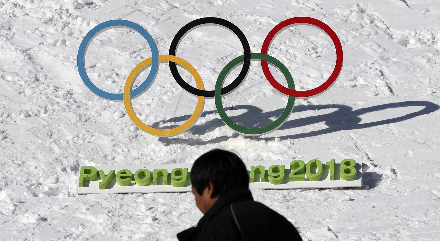 In this Feb. 3, 2017 photo, a man walks by the Olympic rings with a sign of 2018 Pyeongchang Olympic and Paralympic Winter Games in Pyeongchang, South Korea. With five months to go before the opening  ...
