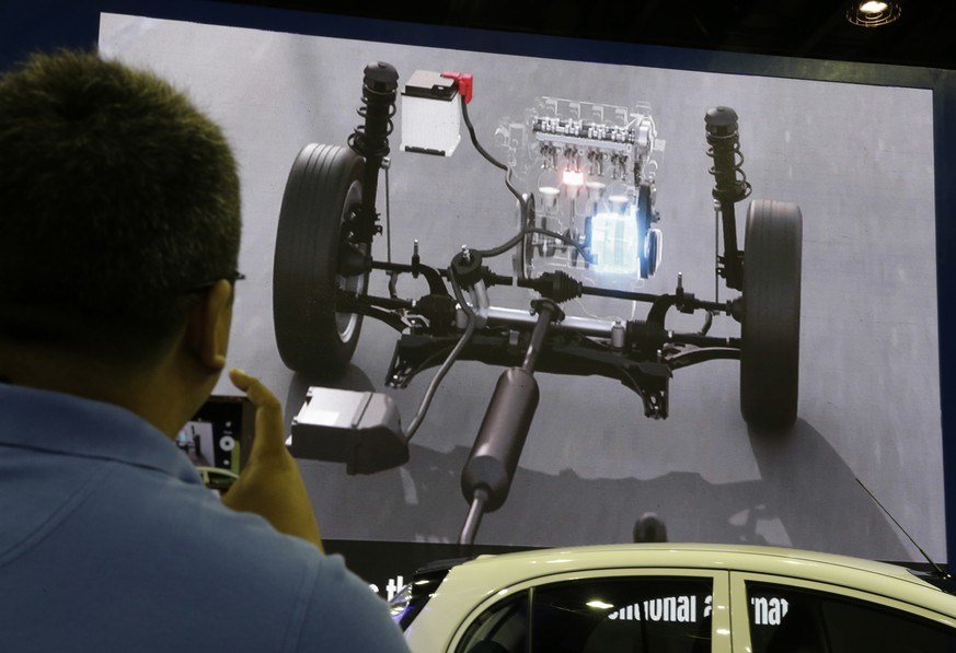 A man looks at a video of the engine of electric and hybrid cars during the first ASEAN electric vehicle and hybrid summit in Manila, Philippines, Thursday, June 29, 2017. The summit aims to highlight ...