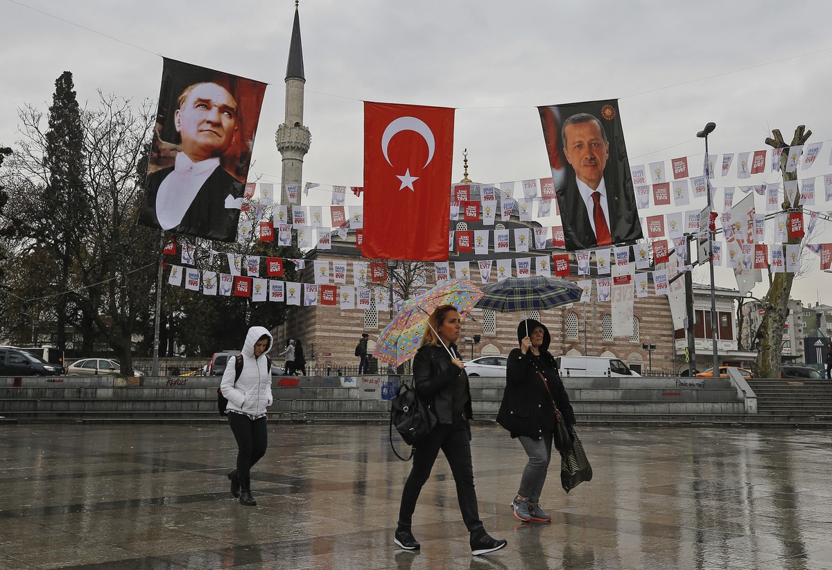 Backdropped by posters of modern Turkey's founder Mustafa Kemal Ataturk, left, and Turkey's President Recep Tayyip Erdogan, right, people walk in Istanbul, Friday, April 7, 2017. Turkey is h ...
