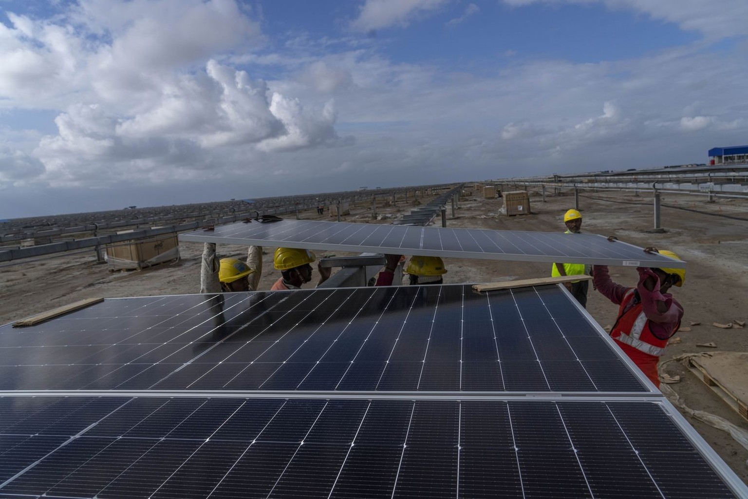Workers install solar panels at the under-construction Adani Green Energy Limited&#039;s Renewable Energy Park in the salt desert of Karim Shahi village, near Khavda, Bhuj district near the India-Paki ...