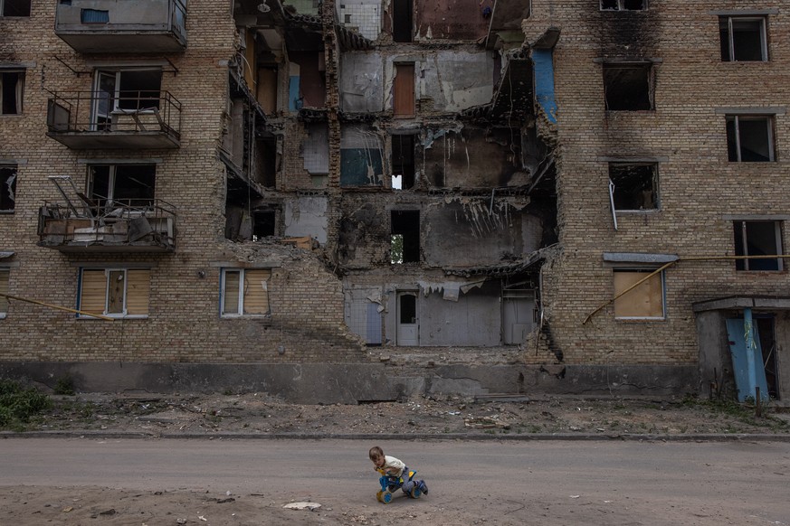 epa10134547 A child plays in front of a damaged residential building in Horenka, Kyiv (Kiev) region, Ukraine, 17 June 2022. (Issued 23 August 2022). Ukraine marks, on 24 August 2022, six months since ...