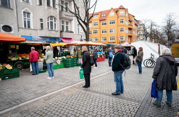 19.03.2020, Berlin: Mit Abstand stehen Passaten in der Schlange vor einem Obst- und Gemüsestand auf dem Wochenmarkt im Berliner Stadtteil Friedenau. Um die Ausbreitung des neuartigen Coronavirus zu ve ...