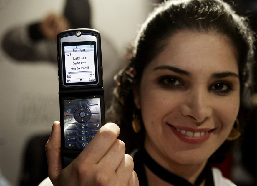 Motorola representative Nazee Hoglund from Liberty, Ill., holds a new Motorola RAZR V3i, at the Motorola booth Saturday, Jan. 7, 2006, at the International Consumer Electronics Show, CES, in Las Vegas ...