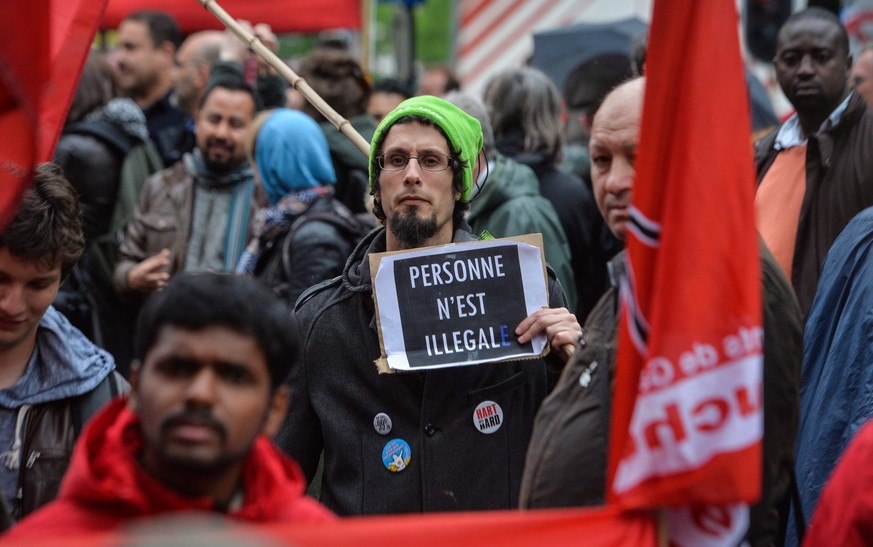 epa04731600 A man holds a banner rading &#039;No One Is Illegal&#039; during a protest for the regularization of all migrants without papers (sans-papiers) in Brussels, Belgium, 03 May 2015. The prote ...