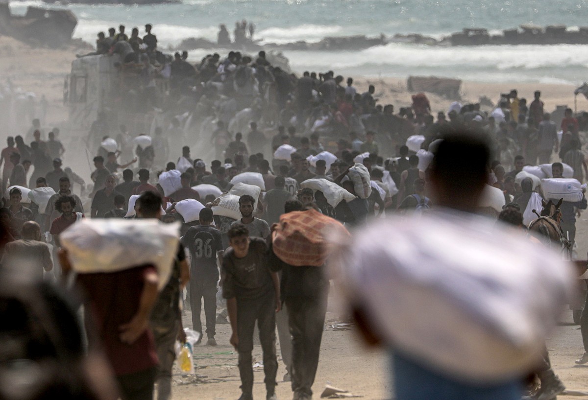 epa12290452 Internally displaced Palestinians carry bags of flour near a food distribution point in Zikim, northern Gaza Strip, 08 August 2025. Humanitarian organizations have warned of an imminent fo ...