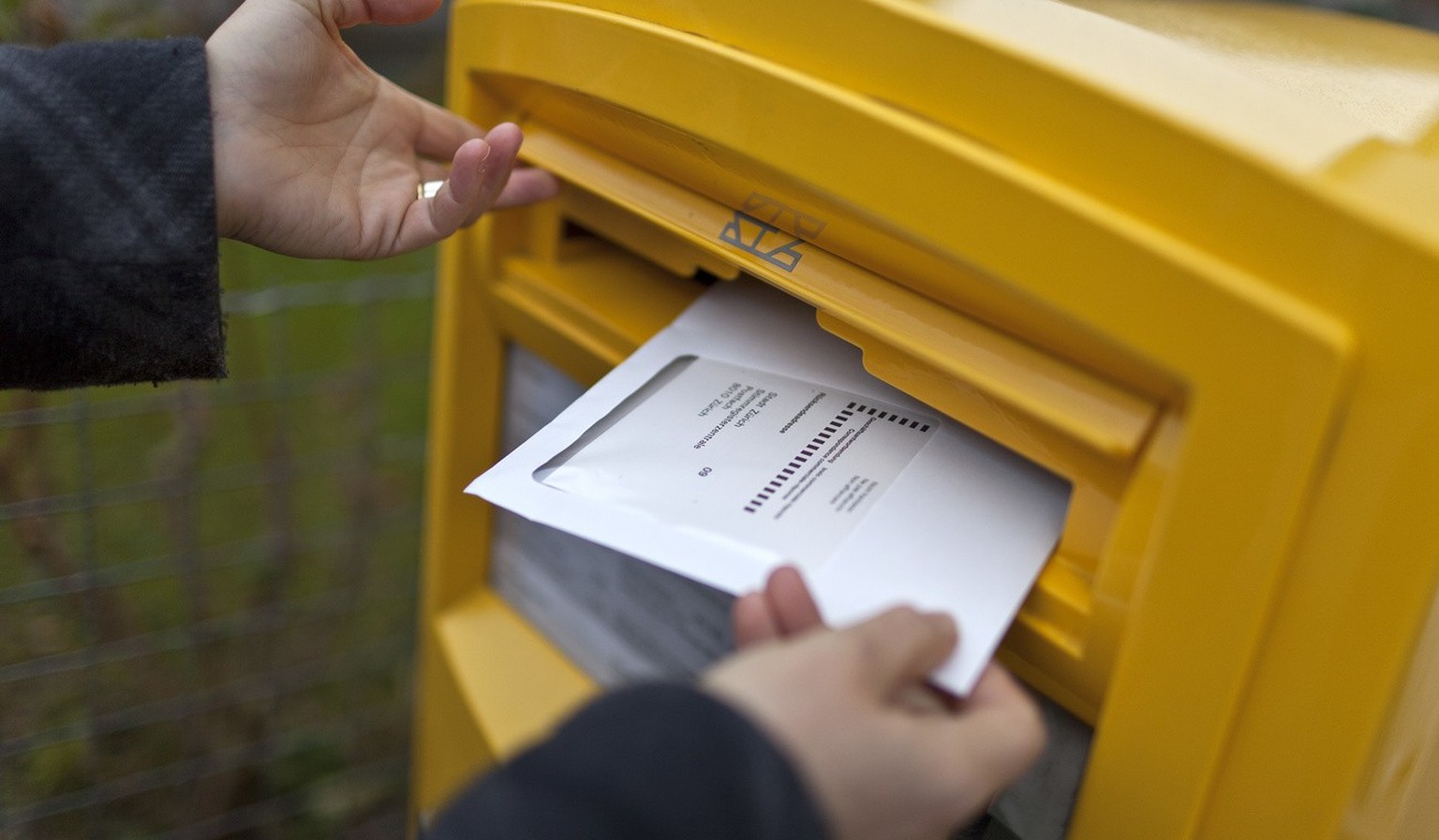 A woman drops an envelope with her vote-by-mail ballot in a letterbox on the occasion of the second tour of the election for the canton of Zurich&#039;s seat in the federal Council of States, pictured ...