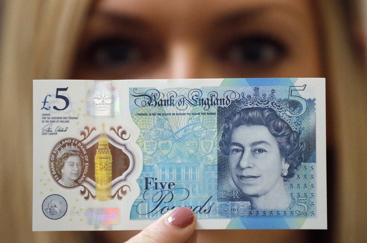 FILE - A Bank of England employee shows the new five pound note at the Bank of England Museum in London, Sept. 6, 2016. As the United Kingdom's reigning monarch, Queen Elizabeth II was depicted o ...