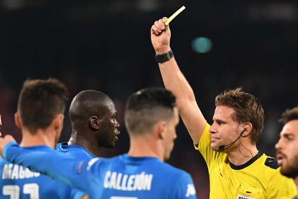 Referee Felix Brych shows the yellow card to Napoli&#039;s Kalidou Koulibaly during the Champions League Group F soccer match between Napoli and Manchester City, at the San Paolo stadium in Naples, It ...