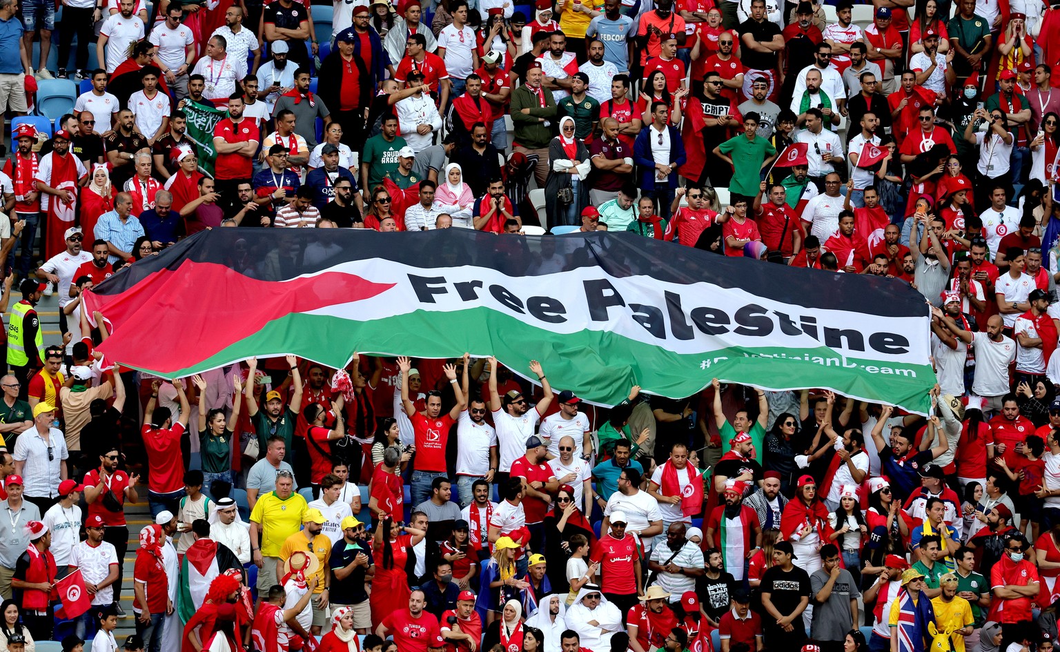 epa10329627 The flag of Palestine is seen among fans of Tunisia in stands during the FIFA World Cup 2022 Group D soccer match between Tunisia and Australia at Al Janoub Stadium in Al Wakrah, Qatar, 26...