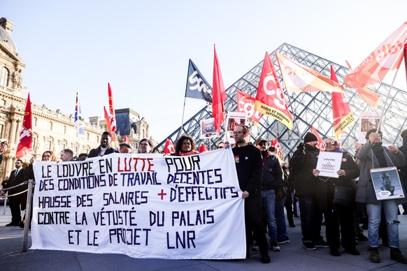 epa12593798 Louvre workers from various unions, including CGT, CFDT, and SUD, hold a banner with the message 'The Louvre fights for decent working conditions, higher wages, and more staff. Agains ...