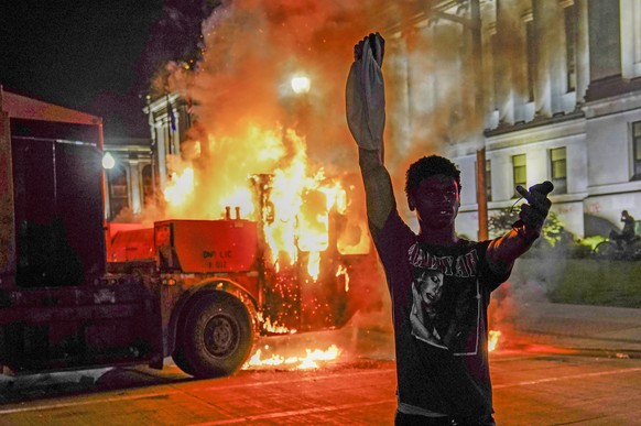 epa08623704 A protestor takes his turn posing in front of a burning garbage truck during a seconed night of unrest in the wake of the shooting of Jacob Blake by police officers, in Kenosha, Wisconsin, ...