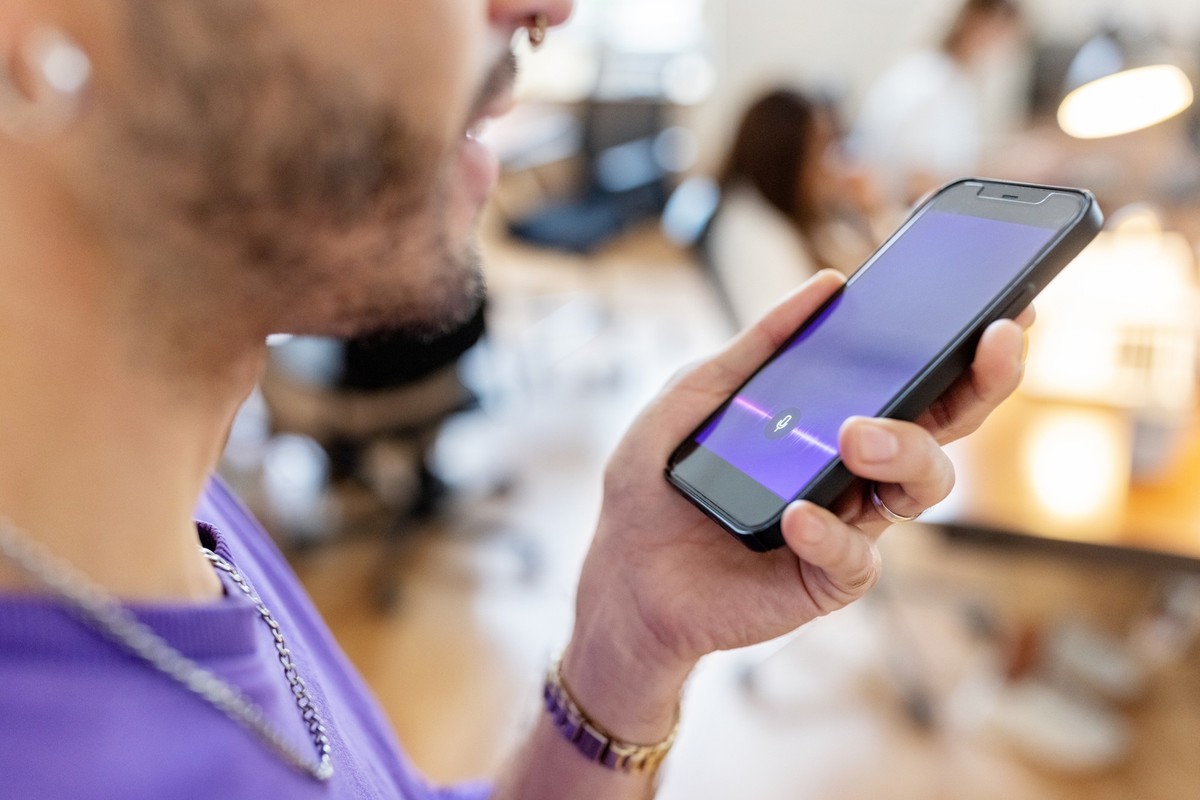 Close-up of man recording voice message on cellphone at office. Cropped shot of businessman recording a voice message on mobile phone.