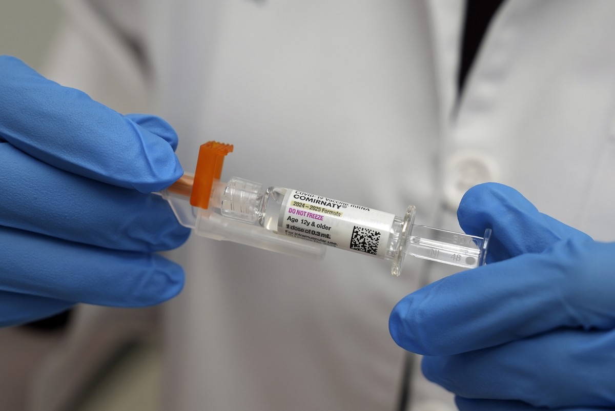 A pharmacist holds a COVID-19 vaccine at a pharmacy in New York, Tuesday, Sept. 24, 2024. (AP Photo/Mary Conlon)