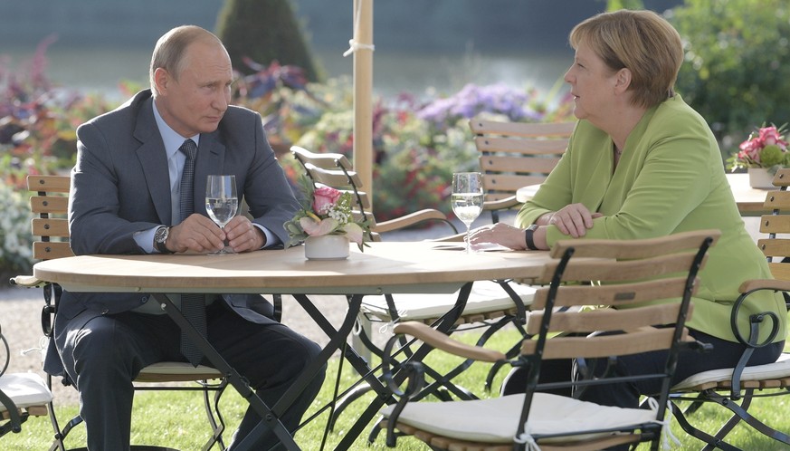 German Chancellor Angela Merkel, right, and Russian President Vladimir Putin talk to each other during their meeting at the government guest house Meseberg in Gransee near Berlin, Germany, Saturday, A ...