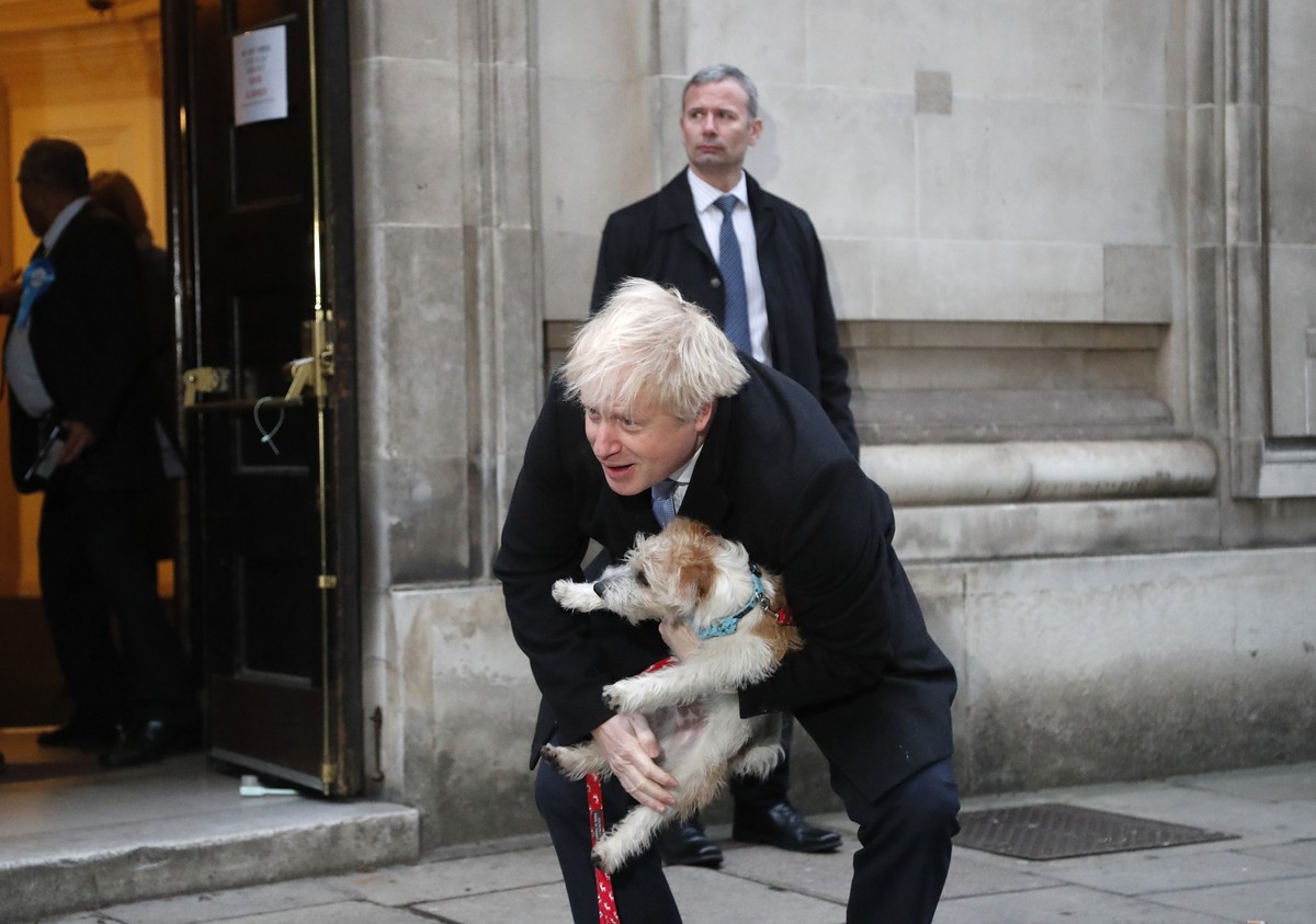 Britain's Prime Minister and Conservative Party leader Boris Johnson holds his dog Dilyn as he leaves after voting in the general election at Methodist Central Hall, Westminster, London, Thursday ...
