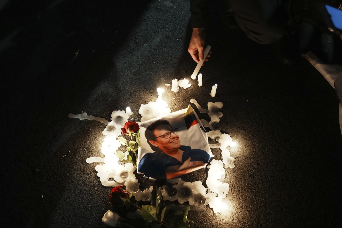 A supporter lights a candle around a photo of slain candidate Fernando Villavicencio during an open-air Mass prior to the closing campaign rally of the "Movement Construye" party in Quito, E ...