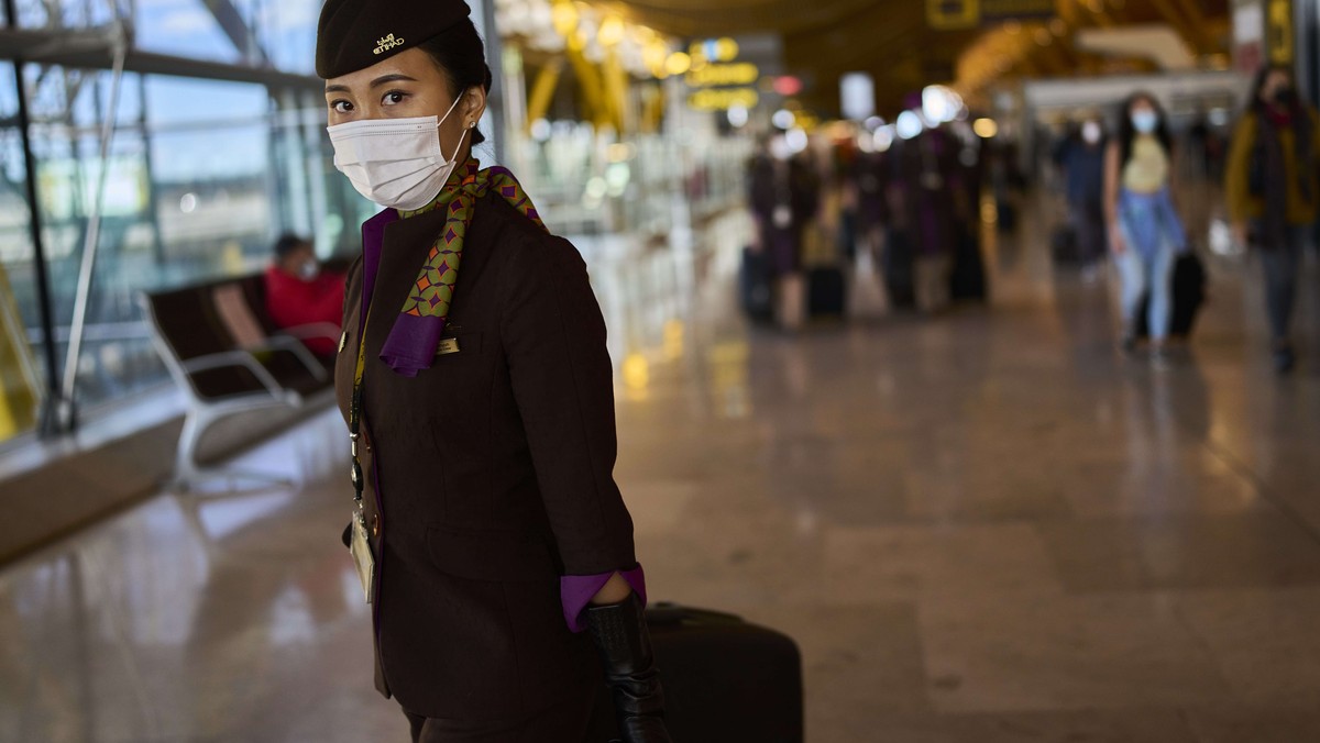 A flight crew member wearing face a mask to prevent the spread of coronavirus walk along the Adolfo Suarez-Barajas international airport in Madrid, Spain, Thursday, Dec. 2, 2021. The coronavirus' ...