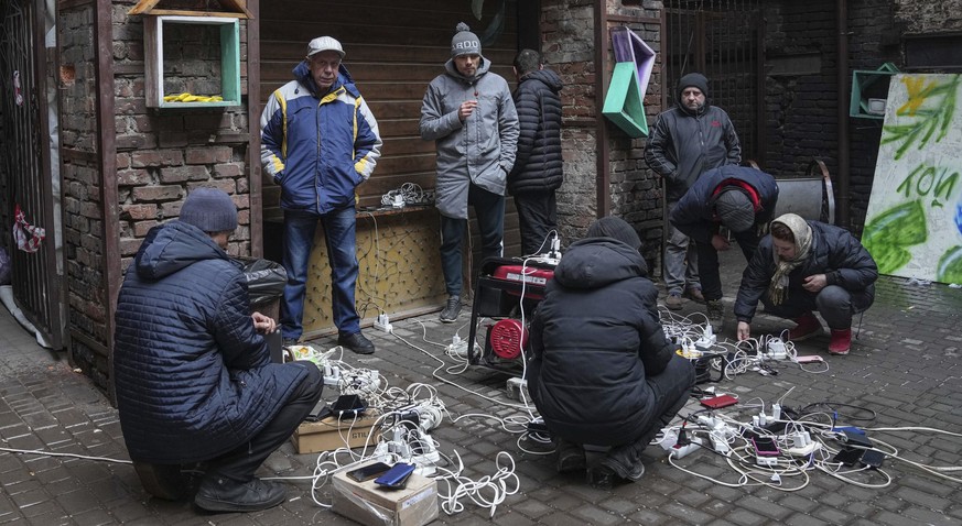 People charge their phones in a yard in Mariupol, Ukraine, Sunday, March 6, 2022. (AP Photo/Evgeniy Maloletka)