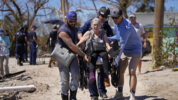 Rescuers help evacuate Suzanne Tomlinson, a resident who rode out the storm, as they carry her to a waiting boat in the aftermath of Hurricane Ian on Pine Island, Fla., Sunday, Oct. 2, 2022. The only  ...