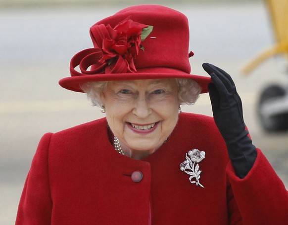 FILE - Britain&#039;s Queen Elizabeth II holds on to her hat in high winds as she arrives for a visit to RAF Valley, Anglesey, Wales on April 1, 2011. (AP Photo/Christopher Furlong, File)