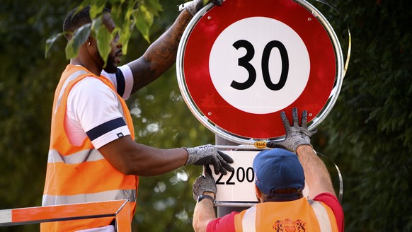 Deux employes de la ville de Lausanne mettent en place un panneau de circulation signalant l&#039;interdiction de rouler a plus de 30km/h, de 22h00 a 06h00, ce lundi 13 septembre 2021 dans une rue de  ...
