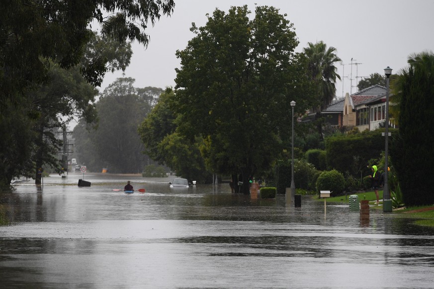 epa09089032 A person uses a kayak to navigate flooded Old Hawkesbury Road near Pitt Town and Windsor in the North West of Sydney, New South Wales, Australia, 22 March 2021. Thousands of residents are  ...