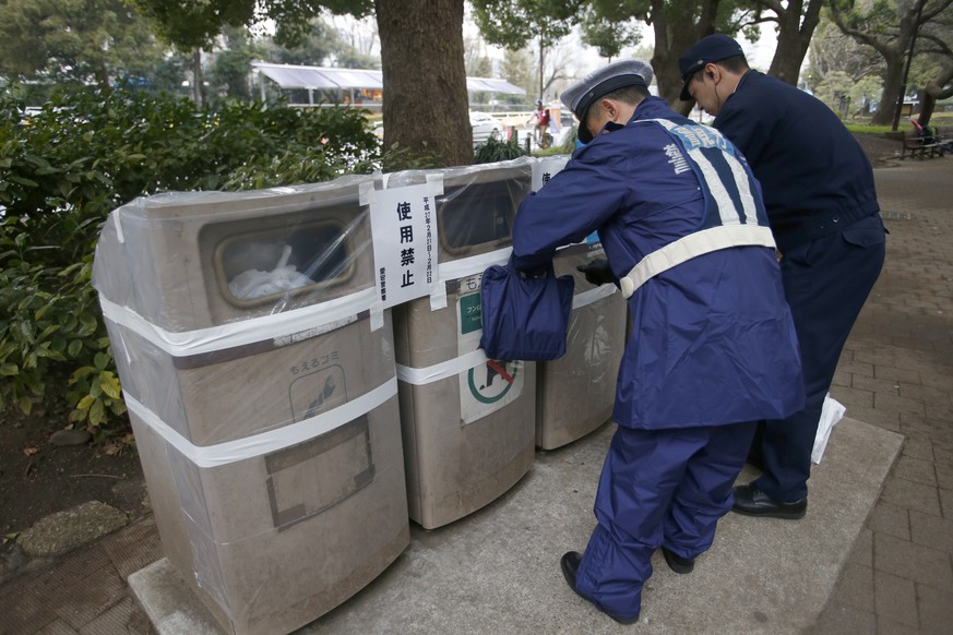 Sicherheitsleute kleben aus Sicherheitsgründen einige der wenigen Abfalleimer, die es in Tokio gibt, zu.
