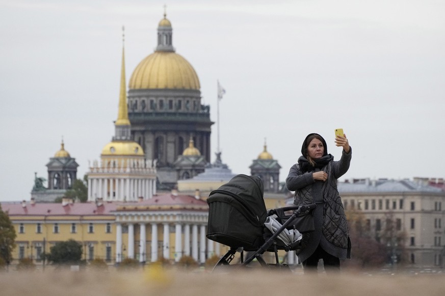A woman takes a selfie photo in St. Petersburg, Russia, Tuesday, Oct. 11, 2022, with the Admiralty building and the St. Isaac&#039;s Cathedral in background. (AP Photo/Dmitri Lovetsky)