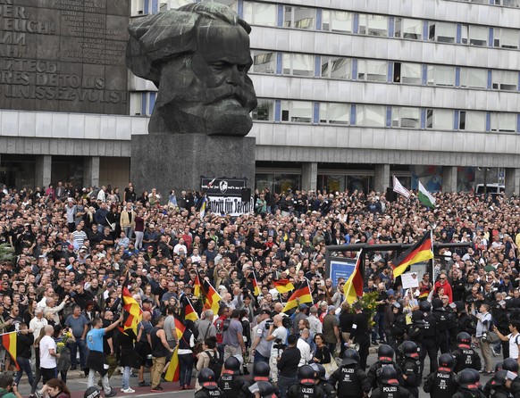 epa06976862 German police in riot gear patrols around the statue of Karl Marx as right wing protesters gather at the place where a man was stabbed overnight 25 August 2018, in Chemnitz, Germany, 27 Au ...