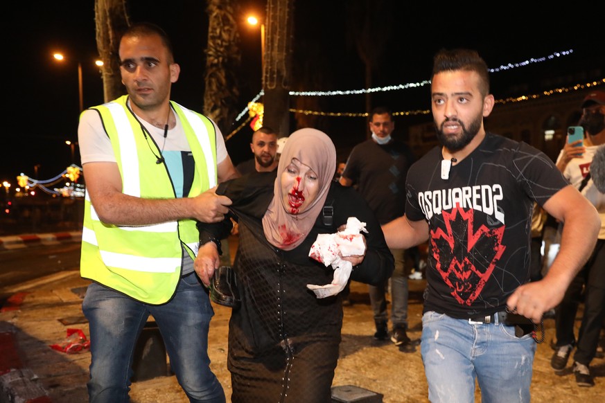Eine verletzte palästinensische Frau wird von Helfern in Sicherheit gebracht.