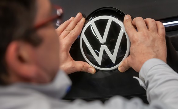 epa08247050 A Volkswagen employee fixes the VW logo on a Volkswagen ID.3 car in the assembly line during the production of the electric car at the Volkswagen (VW) vehicle factory in Zwickau, Germany,  ...