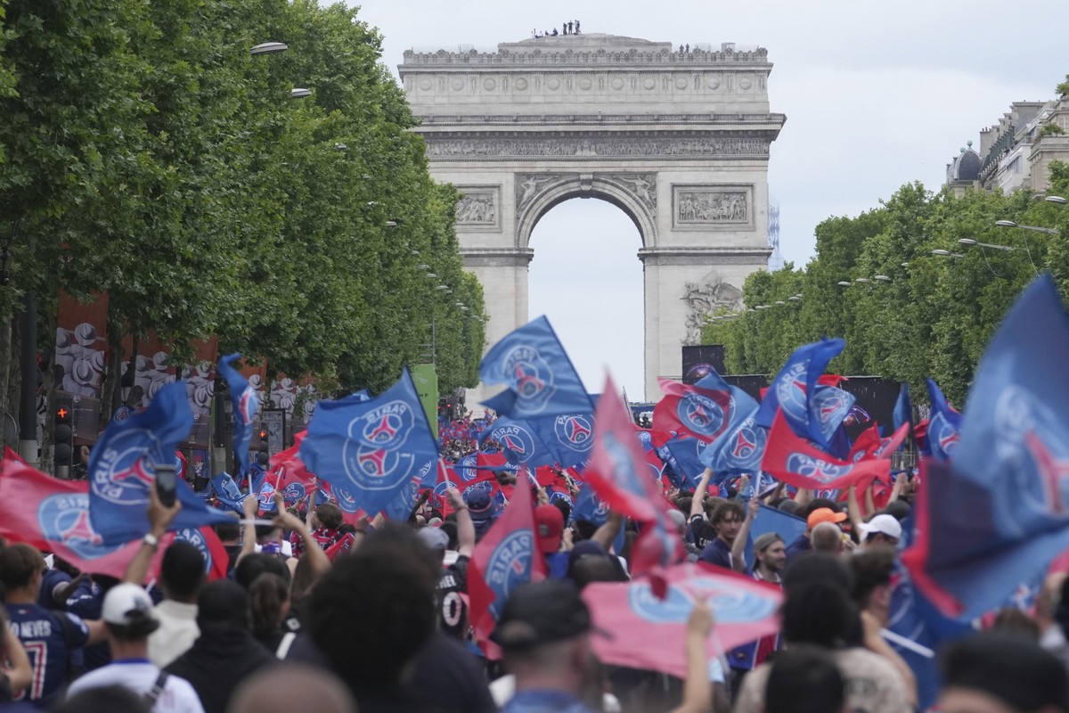 PSG supporters invade the Champs-Elysees avenue, with de Arc de Triomphe in background, before a PSG players' parade after the team won the Champions League final soccer match between Paris Saint ...