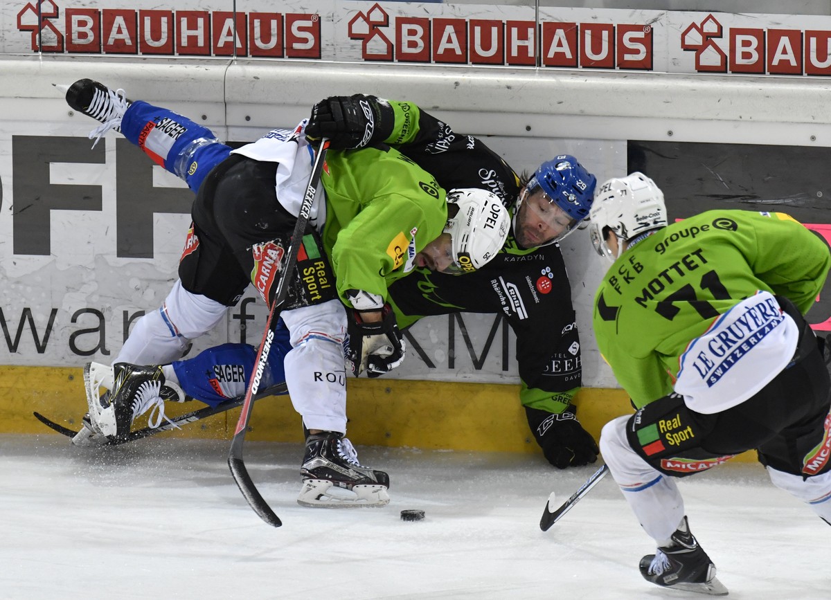 Der Davoser Beat Forster, Mitte, wird von Fribourgs Benjamin Neukom, links, und Killian Mottet an die Bande gestossen, waehrend dem Eishockey-Qualifikationsspiel der National League A zwischen dem HC  ...