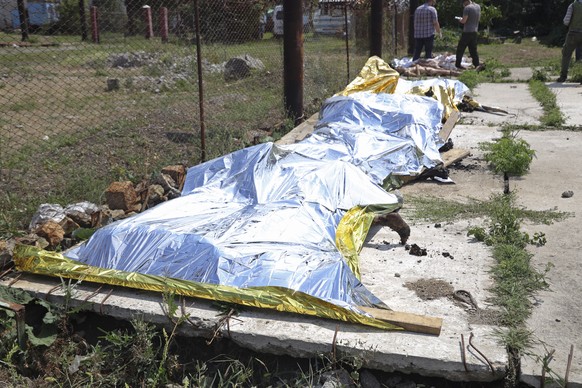 EDS NOTE: GRAPHIC CONTENT - Investigators examine bodies of Ukrainian military prisoners at a prison in Olenivka, in an area controlled by Russian-backed separatist forces, eastern Ukraine, on July 29 ...