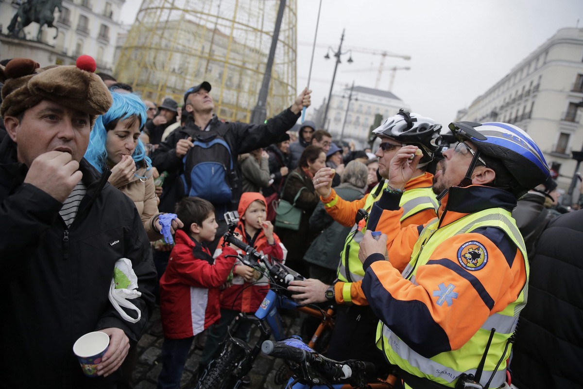 epa05084340 People eat 12 grapes to the sound of noon's 12 strokes at Puerta del Sol square during a rehearsal of New Year's celebrations, in downtown Madrid, Spain, 31 December 2015. About  ...