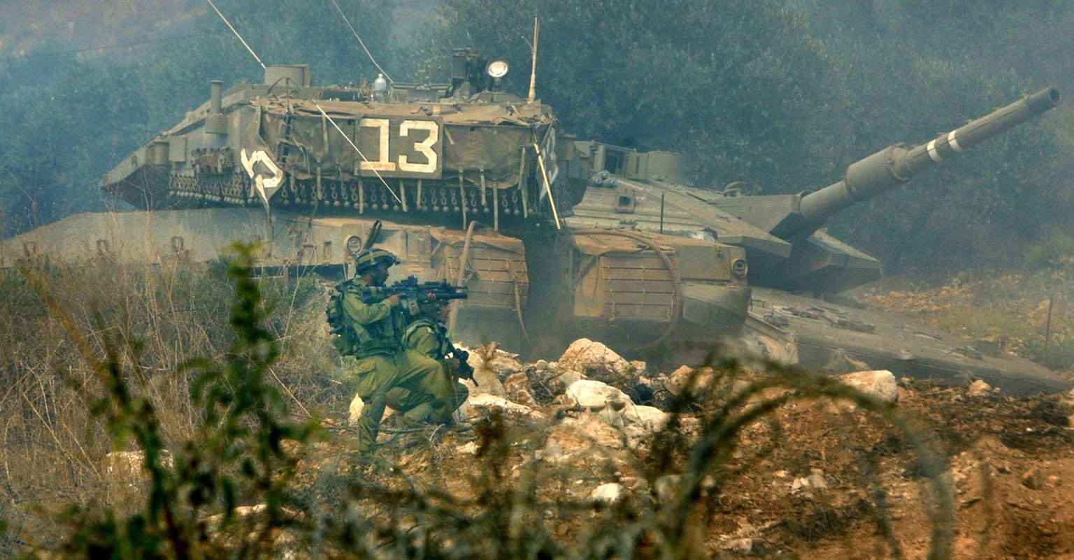 FILE- In this file photo taken on July 31, 2006, Israeli soldiers take positions next to a rocket damaged tank after Hezbollah guerrillas attacked Israeli troops in the Lebanese side of the border wit ...