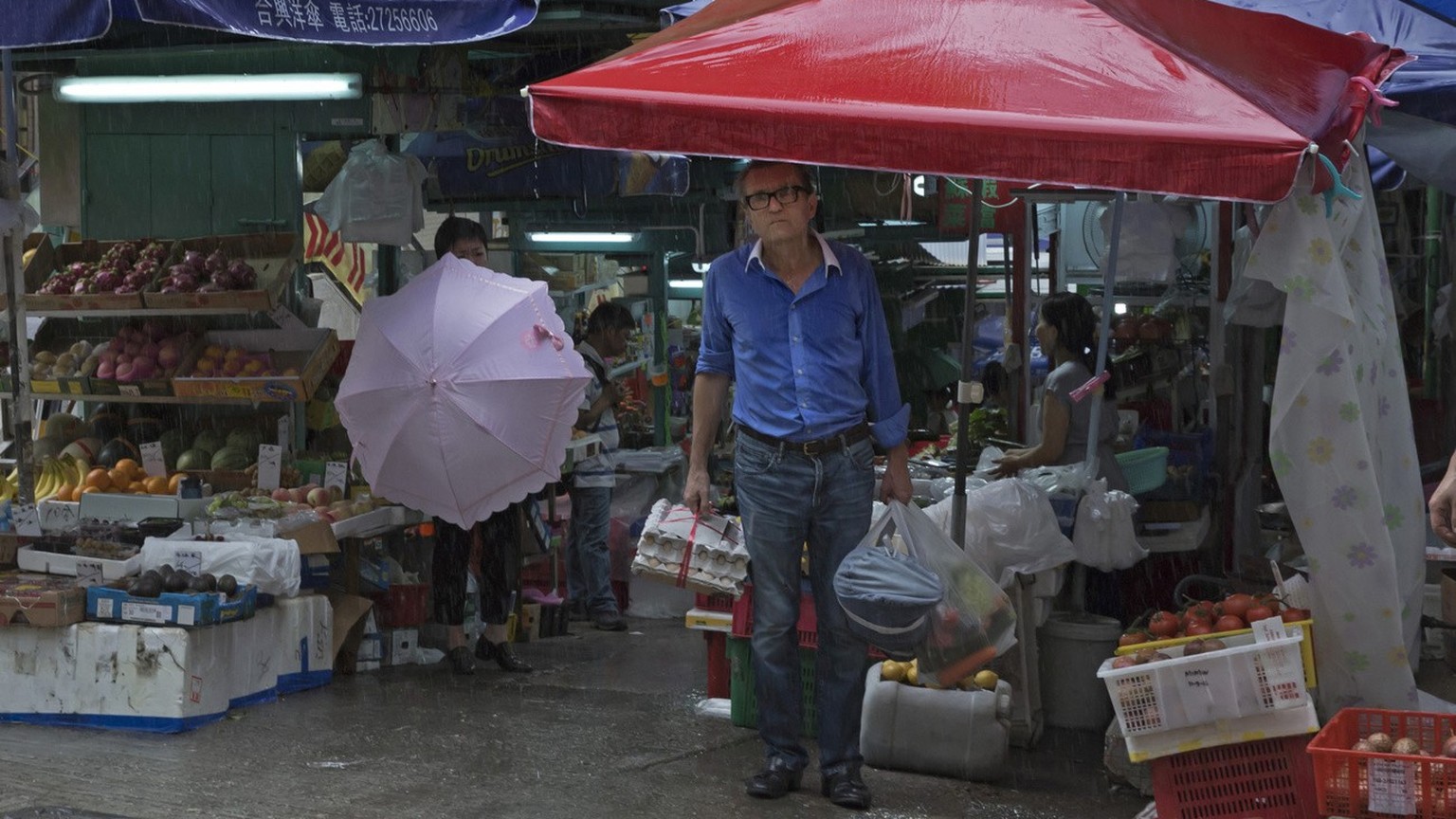 In this June 12, 2017, photo, a man takes shelter from a storm at a local market on the slope in Central district, Hong Kong. Once known as Victoria after the British queen, Hong Kong island&#039;s wa ...