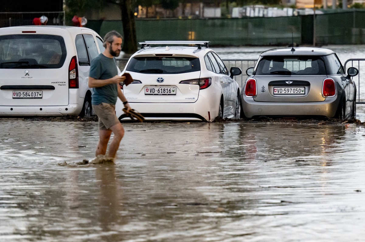 Une personne marche entre des vehicules sur un parking inonde suite a un orage qui a entraine une importante inondation dans le centre ville le mardi 25 juin 2024 a Morges. (KEYSTONE/Laurent Gillieron ...