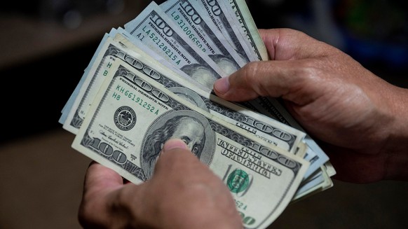 epa08577313 A man counts a wad of dollar bills in Caracas, Venezuela, 30 July 2020 (issued 31 July). The unstoppable inflation that Venezuela is experiencing has led to the inevitable de facto dollari ...