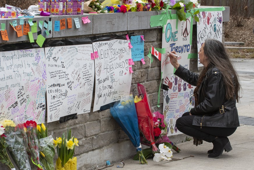 epaselect epa06689507 A woman writes a message at a makeshift memorial across the street from where a man in a rented van plowed into pedestrians on Yonge Street in northern Toronto, Canada, 24 April  ...