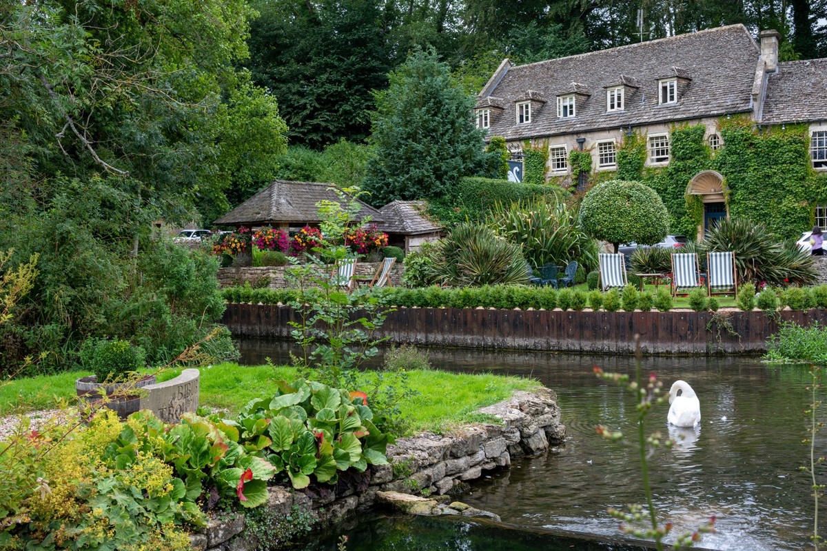 A Beautiful shot of stone cottage with a green garden and a river in Bibury Village