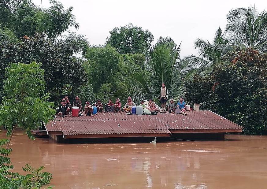 epa06907329 Lao villagers are stranded on a roof of a house after they evacuated floodwaters after the Xe Pian Xe Nam Noy dam collapsed in a village near Attapeu province, Laos, 24 July 2018. Several  ...
