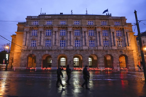 Police officers guard the area as people bring flowers and candles in front of the building of the Philosophy Faculty of Charles University in the center of Prague, Czech Republic, Sunday, December 1.  24, 2023. A...