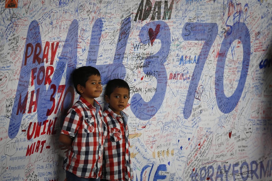 FILE - Two Malaysian children stand in front of a messages board and well wishes on it to people involved with the missing Malaysia Airlines jetliner MH370, in Sepang, Malaysia, on March 16, 2014. Ten ...