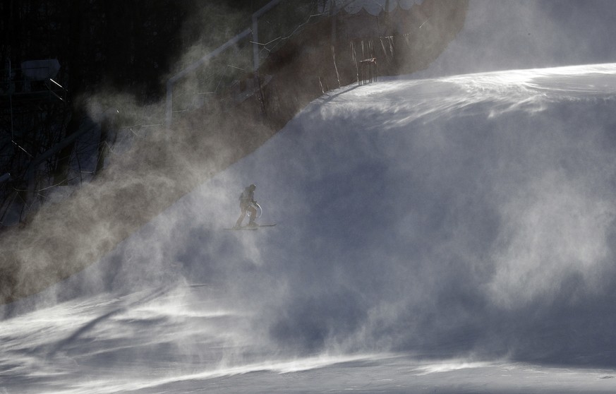 A course worker is shrouded in snow as it blows across the course where the technical events will be held before an inspection by competitors in the women&#039;s giant slalom at the Yongpyong Alpine C ...