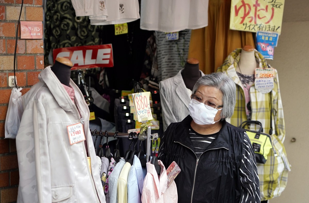 epa08340658 An elderly woman wearing a face mask shops at a clothing store at Sugamo district in Tokyo, Japan, 03 April 2020. Despite the rise of infection cases, Japan's Prime Minister Shinzo Ab ...