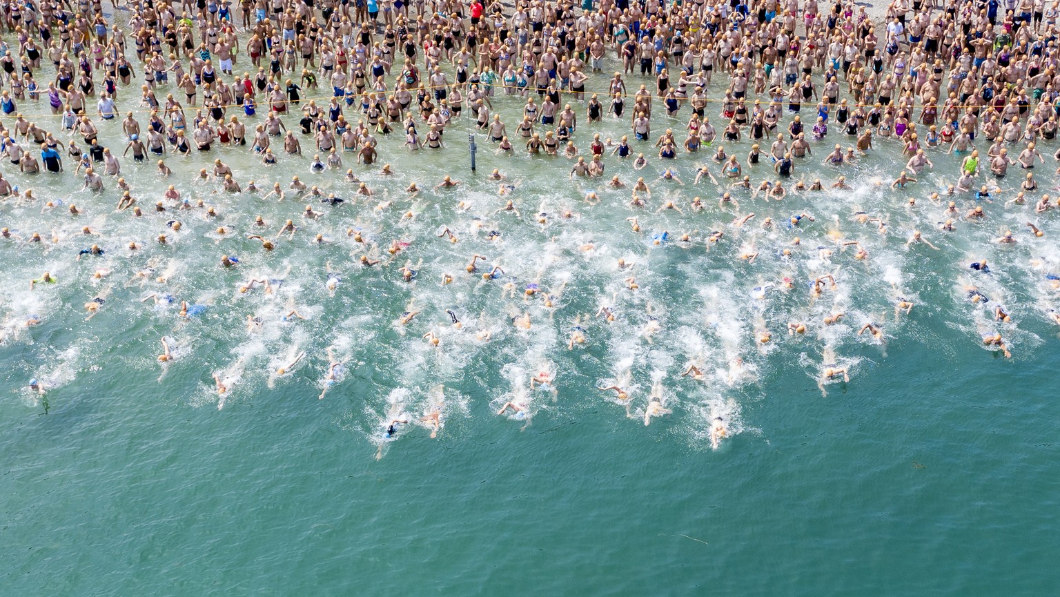 Teilnehmerinnen und Teilnehmer der Zuercher Seeueberquerung stuerzen sich bei hochsommerlichen Temperaturen in das erfrischende Wasser des Zuerichsees, aufgenommen am Mittwoch, 3. Juli 2019 in Zuerich ...