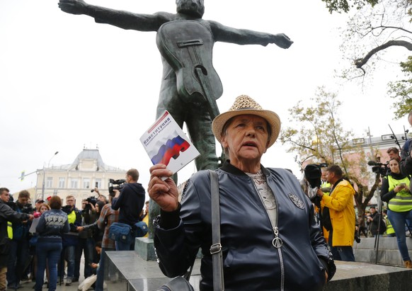 An opposition activist holds the Russian Constitution book in front of the monument to Soviet-era opposition legendary bard Vladimir Vysotsky during a protest in the center of Moscow, Russia, Saturday ...