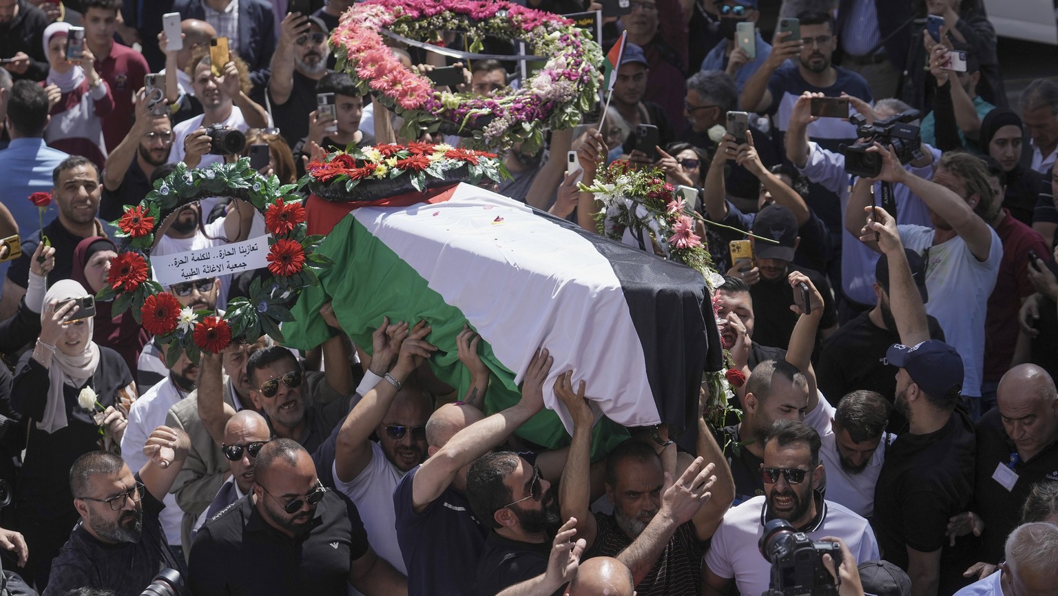 Freunde und Familie tragen den Sarg von Scherin Abu Akleh nach der Autopsie von der Universität in einer dreitägigen Prozession von Nablos im Westjordanland in ein Spital in Ostjerusalem, wo die Leiche bis zur Beerdigung gekühlt werden soll, 12. Mai 2022.