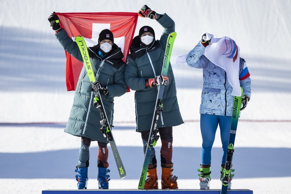 Gold medal winner Ryan Regez of Switzerland, center, silver medal winner Alex Fiva of Switzerland, left, and bronze medal winner Sergey Ridzik of ROC celebrate on the podium with their flags after the ...